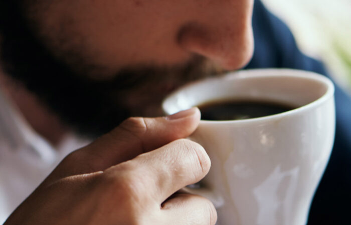 Close-up of a person drinking coffee from a white mug.